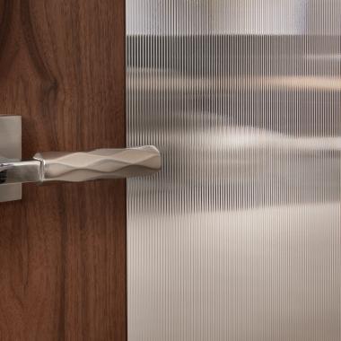 A TM9250 door, in walnut with Nutmeg stain and Groove glass, divides a bathroom from this contemporary study.