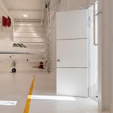 The lounge of this this private jet hangar features TMIR3000 doors in MDF with ½" bright stainless steel inlays.