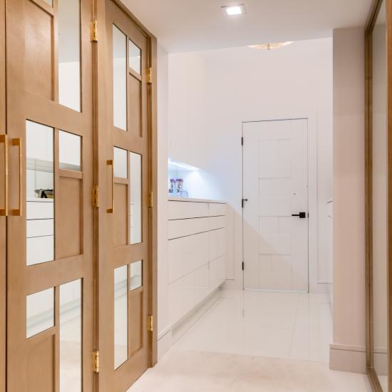 The designer added glamour to this walk-in closet by custom applying plant-ons and mirrors to TS3000 doors in MDF.