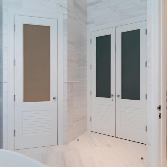 A master bath features TS2060 doors in MDF with Roman Ogee (OG) sticking, Raised (A) panel and Frosted Glass. The bottom panels have been replaced with false louver panels.