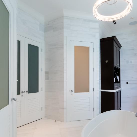 A master bath features TS2060 doors in MDF with Roman Ogee (OG) sticking, Raised (A) panel and Frosted Glass. The bottom panels have been replaced with false louver panels.