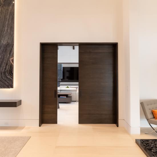 A pair of TMIR3080 pocket doors, in quarter sawn white oak with ¼" kerf cut reveals, open to a family room. Builder provided stain finish.