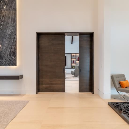 A pair of TMIR3080 pocket doors, in quarter sawn white oak with ¼" kerf cut reveals, open to a family room. Builder provided stain finish.