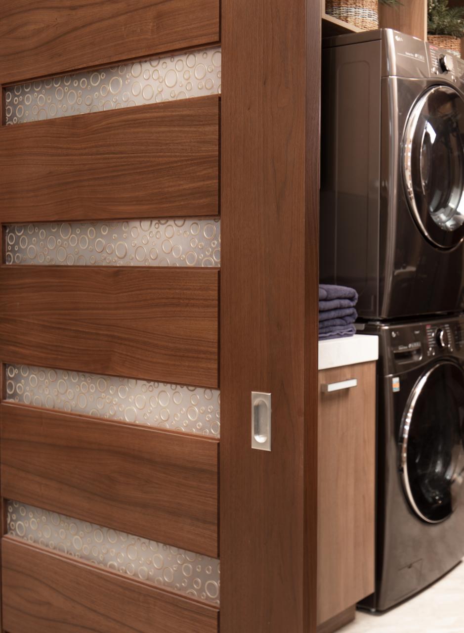 A TM9350 barn door in walnut with Nutmeg stain and Bamboo Rings resin conceals the laundry room from the dining room.