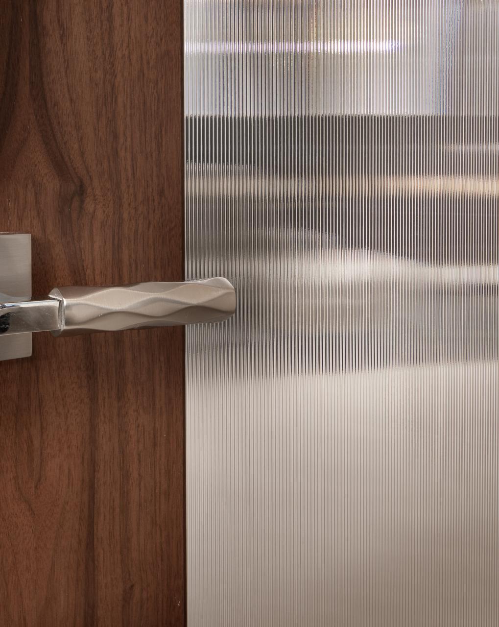 A TM9250 door, in walnut with Nutmeg stain and Groove glass, divides a bathroom from this contemporary study.