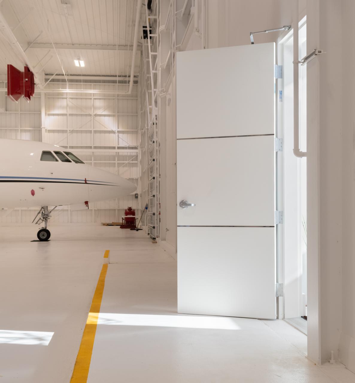 The lounge of this this private jet hangar features TMIR3000 doors in MDF with ½" bright stainless steel inlays.