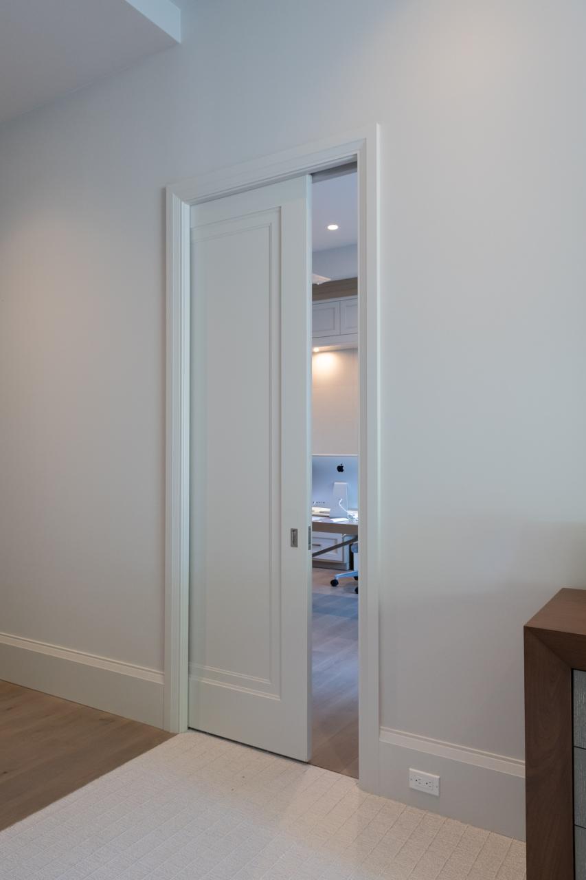 A TS1000 pocket door, in MDF with Miracle (MR) moulding and flat (C) panel, opens from the master bedroom to a private office.