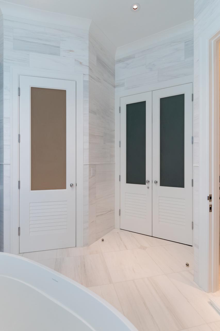 A master bath features TS2060 doors in MDF with Roman Ogee (OG) sticking, Raised (A) panel and Frosted Glass. The bottom panels have been replaced with false louver panels.