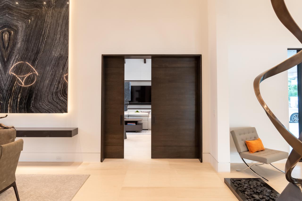 A pair of TMIR3080 pocket doors, in quarter sawn white oak with ¼" kerf cut reveals, open to a family room. Builder provided stain finish.