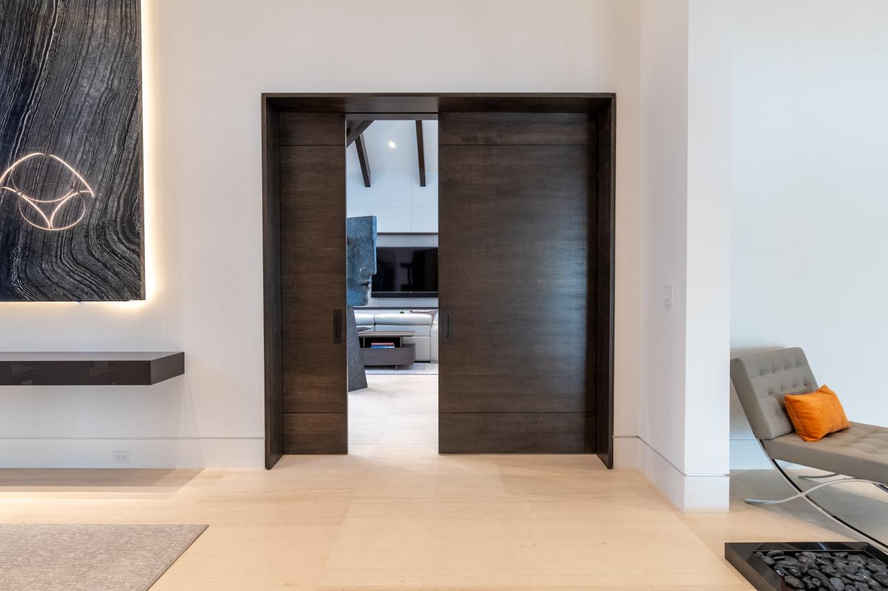 A pair of TMIR3080 pocket doors, in quarter sawn white oak with ¼" kerf cut reveals, open to a family room. Builder provided stain finish.