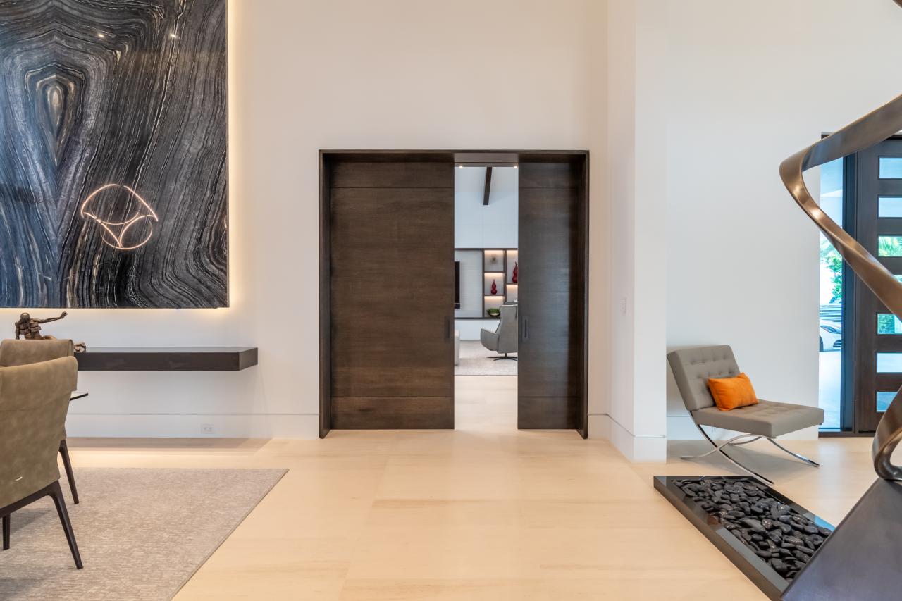 A pair of TMIR3080 pocket doors, in quarter sawn white oak with ¼" kerf cut reveals, open to a family room. Builder provided stain finish.