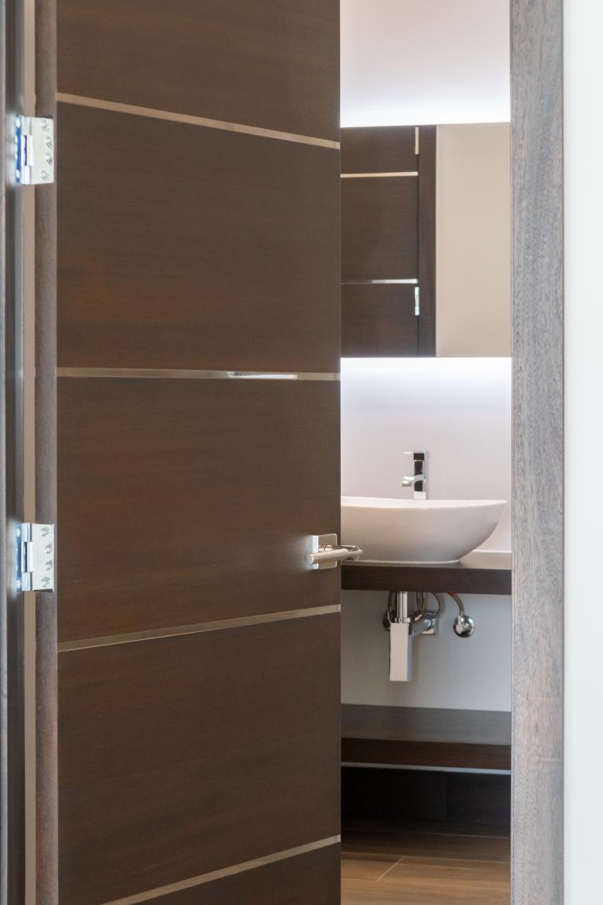 An attached bathroom features TMIR6000 doors in mahogany with ½" bright stainless steel inlay. Builder provided stain finish.