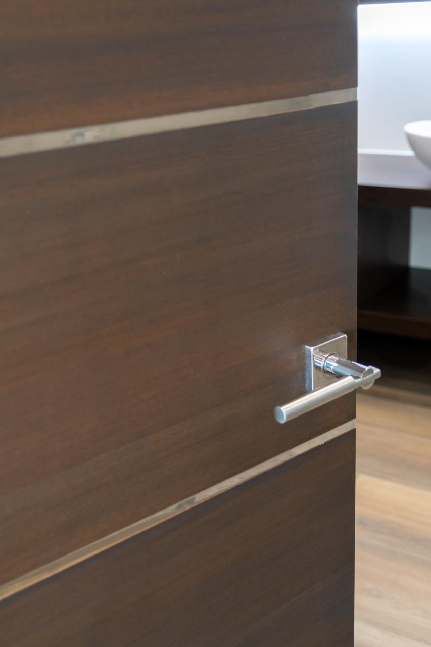 An attached bathroom features TMIR6000 doors in mahogany with ½" bright stainless steel inlay. Builder provided stain finish.