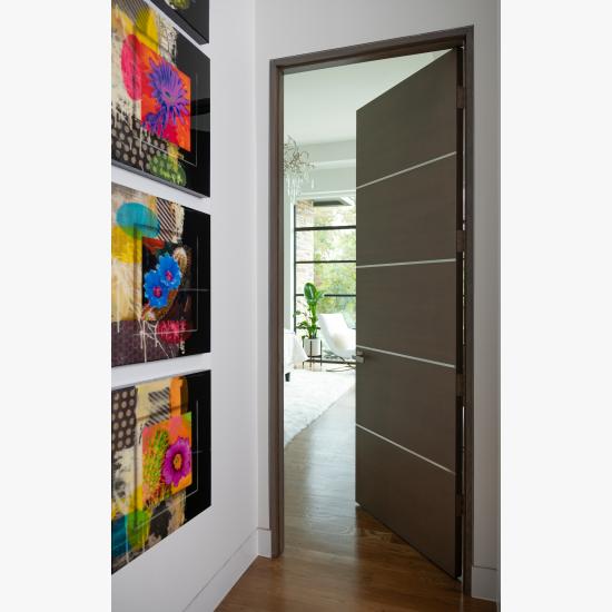 Bedroom featuring a TMIR5000 door in quarter sawn white oak with Grey Mist stain and ½" bright stainless steel inlays.