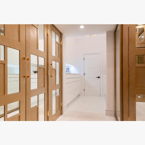 The designer added glamour to this walk-in closet by custom applying plant-ons and mirrors to TS3000 doors in MDF.