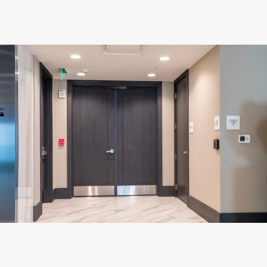 Condominium tower featuring TS1000 doors, in rift sawn white oak with Quirk (QM) moulding and Flat (C) panel in lobby.