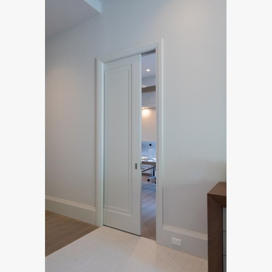 A TS1000 pocket door, in MDF with Miracle (MR) moulding and flat (C) panel, opens from the master bedroom to a private office.