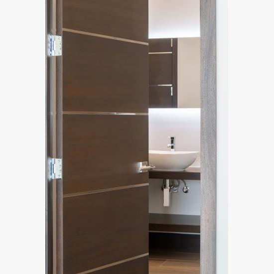 An attached bathroom features TMIR6000 doors in mahogany with ½" bright stainless steel inlay. Builder provided stain finish.