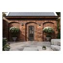Brick courtyard with arched masonry details, black-framed entry door, decorative wall lanterns, large flowering topiary planters, and stone tile patio.