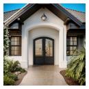 FL112-ES501 Resilient Wood Entry System with Cove & Bead sticking, raised panels, and clear glass, featured in an arched double-door entry on a modern style home