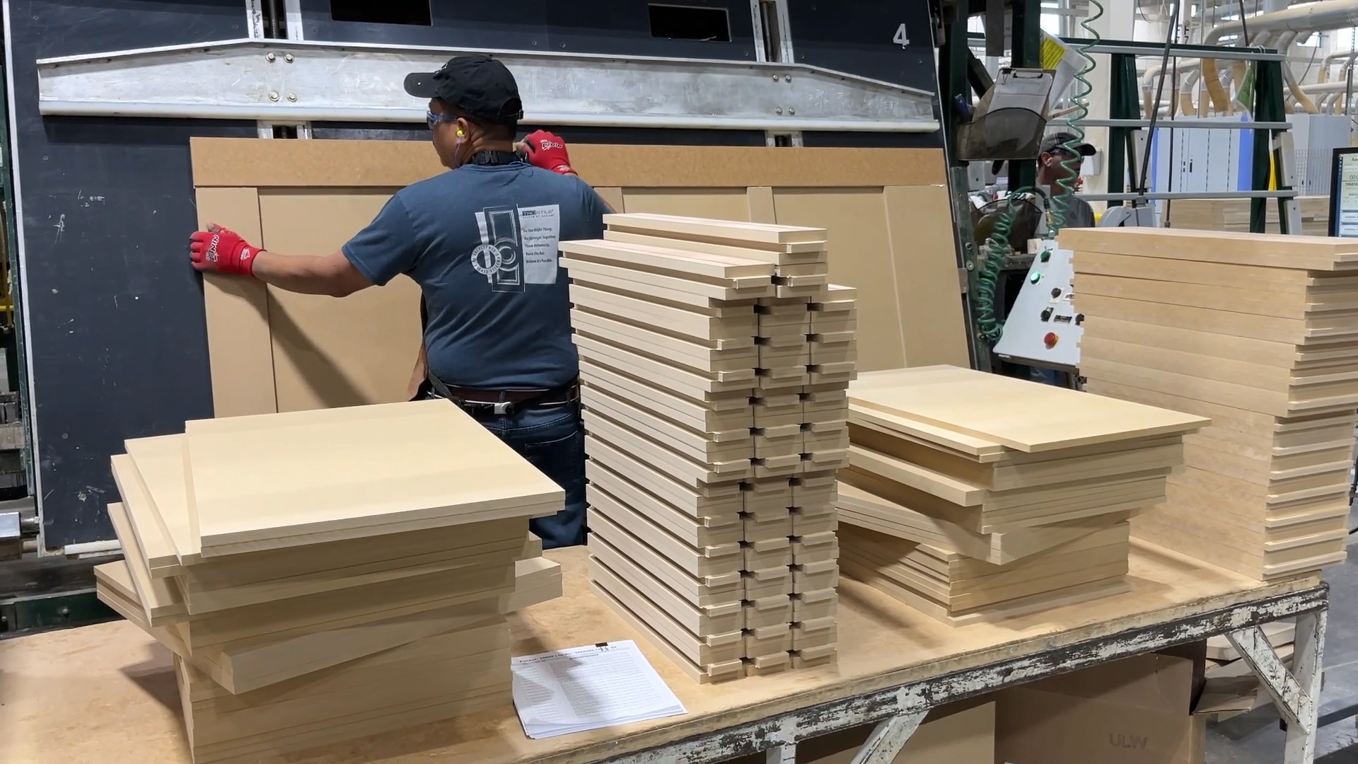 Employee assembles MDF door components into an industrial clamping machine
