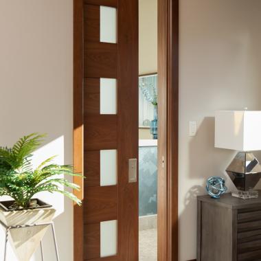 A TM9400 door, in walnut with Nutmeg stain and Frosted glass, divides the bathroom from the rest of this guest suite