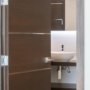 An attached bathroom features TMIR6000 doors in mahogany with ½" bright stainless steel inlay. Builder provided stain finish.