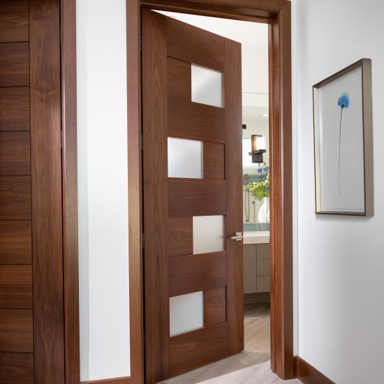 This guest room features a TM9430 door, in walnut with Nutmeg stain and Flow glass, that opens to an adjacent bathroom